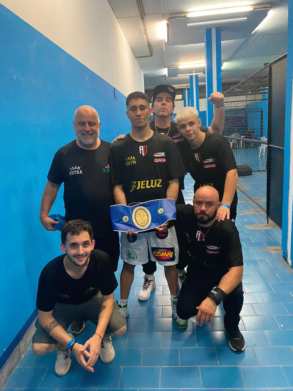 El boxeador junto con su equipo tras quedarse con el cinturón de campeón.