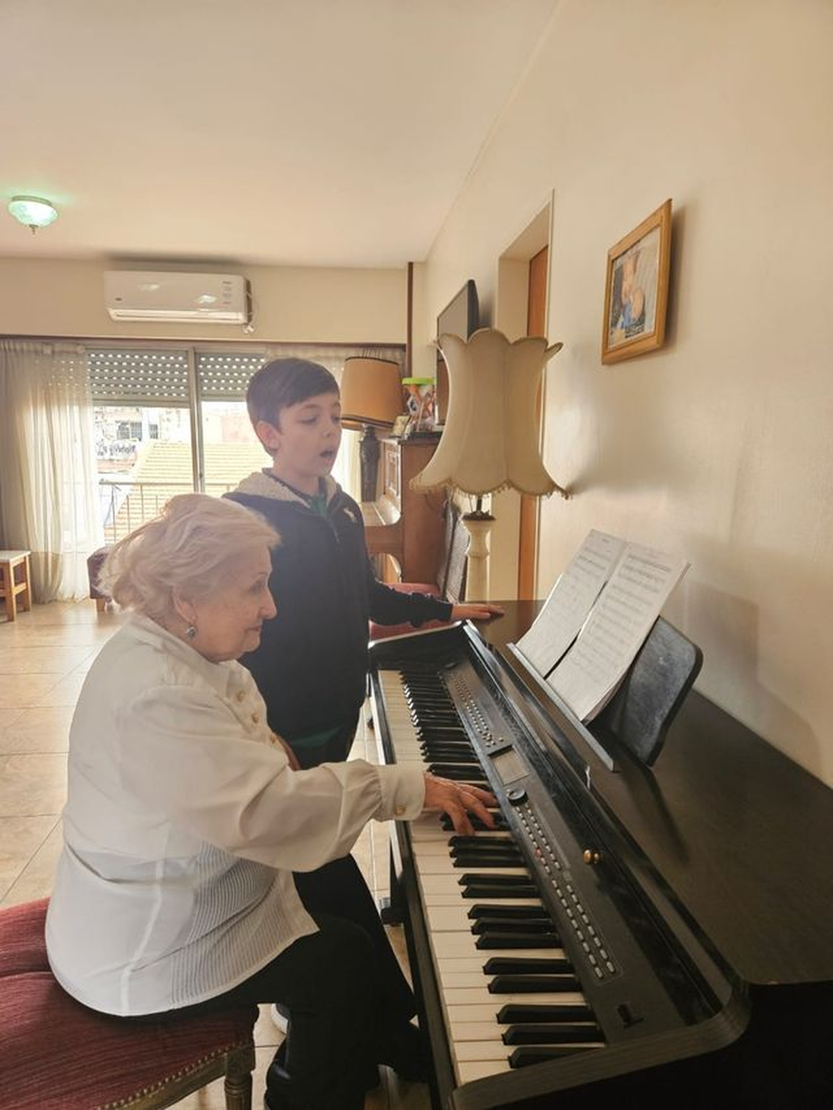Guillermo canta junto a su abuela, quien lo acompaña con el piano.