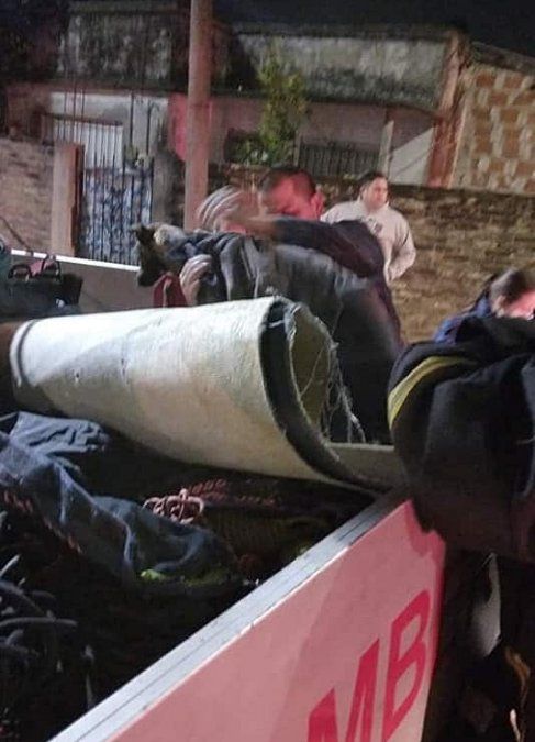 Bomberos y vecinos secan al perro y lo consuelan tras el rescate.