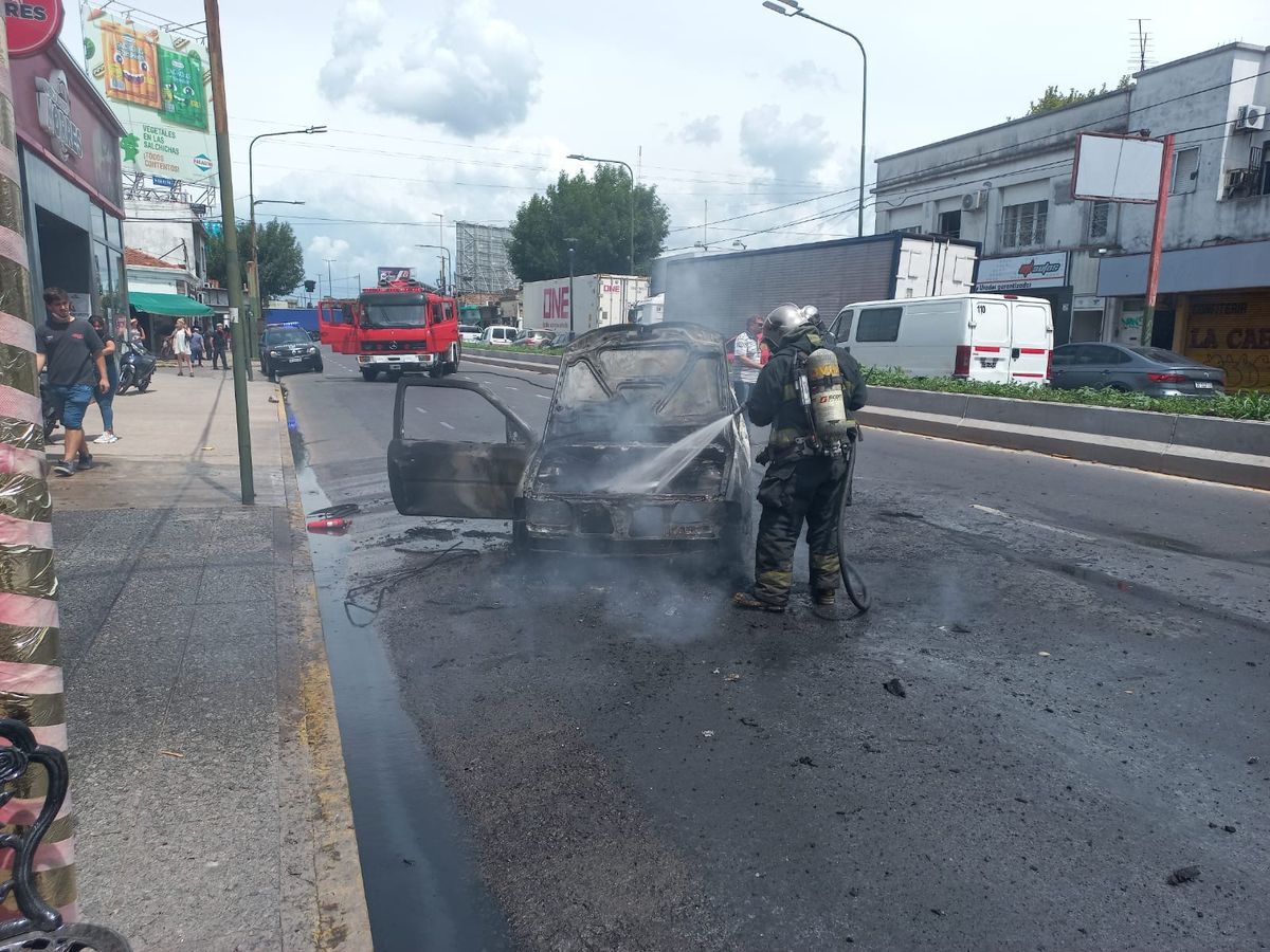 Bomberos de Lomas de Zamora apagan el incendio del auto sobre Hipólito Yrigoyen.