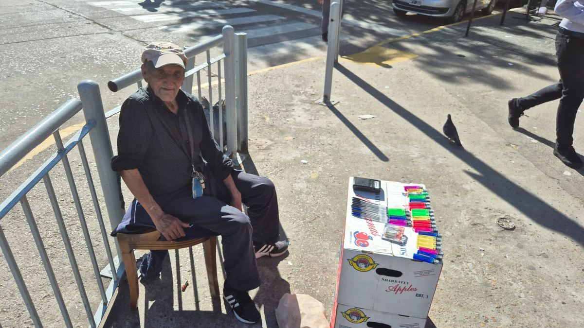 El jubilado ofrece promociones de útiles y asegura que seguirá en la esquina hasta que la economía mejore.